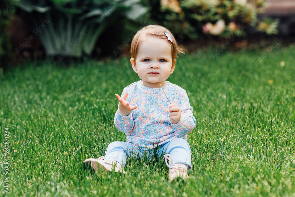 Smiling girl on the meadow looking right at camera and holding grass in hands, beautiful little baby. Smiling girl on the meadow looking right at camera and holding grass in hands, beautiful little baby.