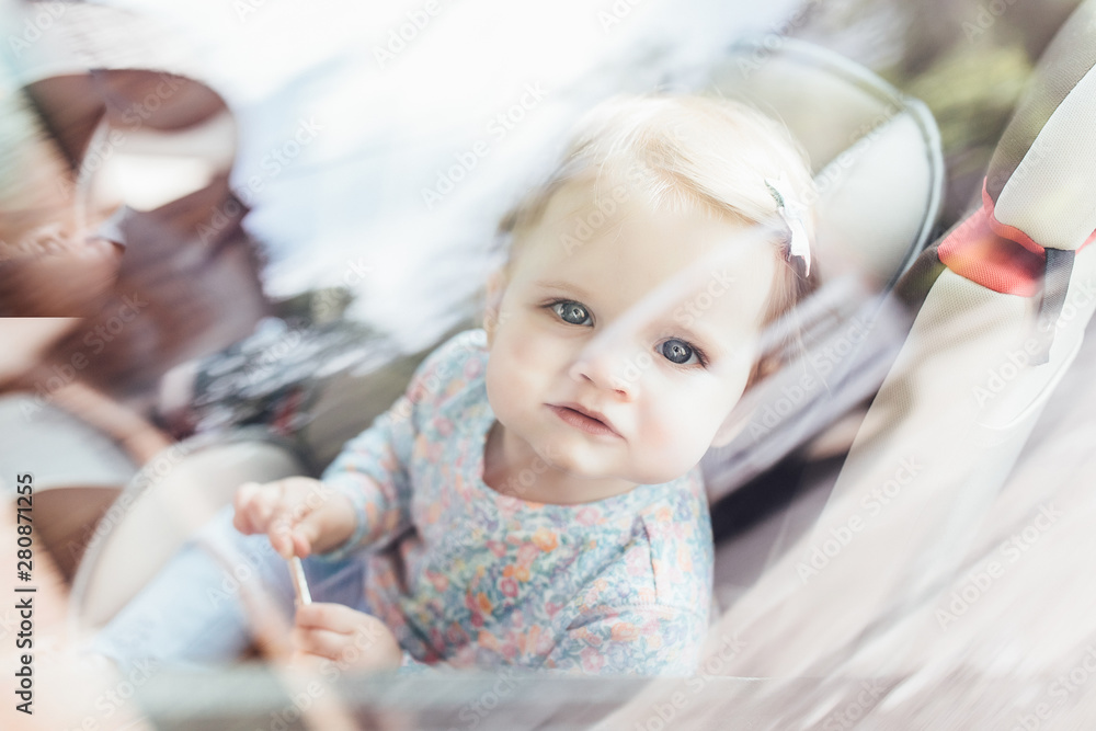 Fototapeta premium Cute little child girl sitting in safety seat inside car. Danger prevention.