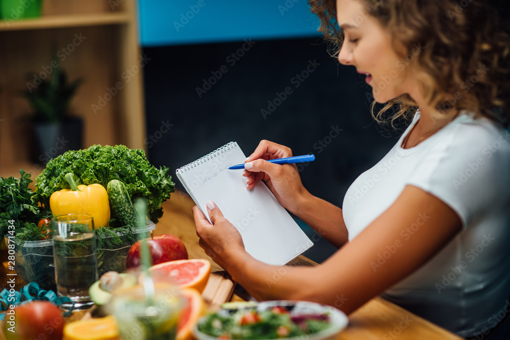 Nutritionist working in office. Doctor writing diet plan on table and using vegetables. Sport trainer. - obrazy, fototapety, plakaty 