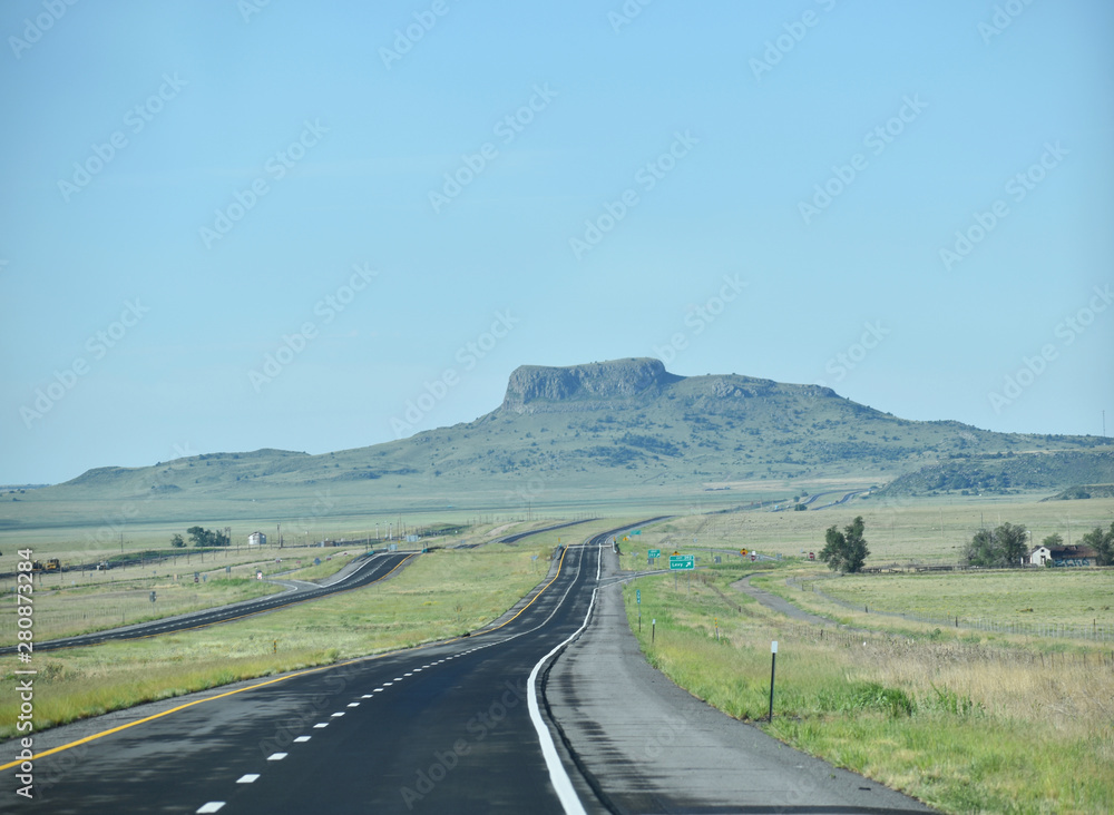 Endless ribbon of blacktop heading towards a mesa butte in New Mexico