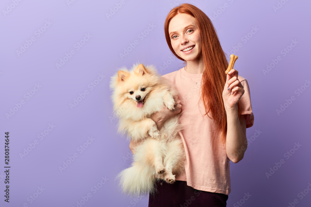 charming good looking woman in stylish casual clothes controlling the food of her pet, right food ration, diet. copy space, isolated blue background, studio shot