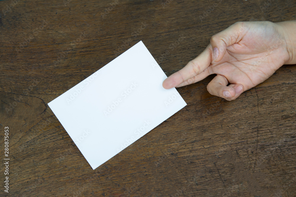 Obraz premium A6 Flyer / Postcard / Invitation Mock-Up - hands holding a blank flyer on a on a wooden table background.
