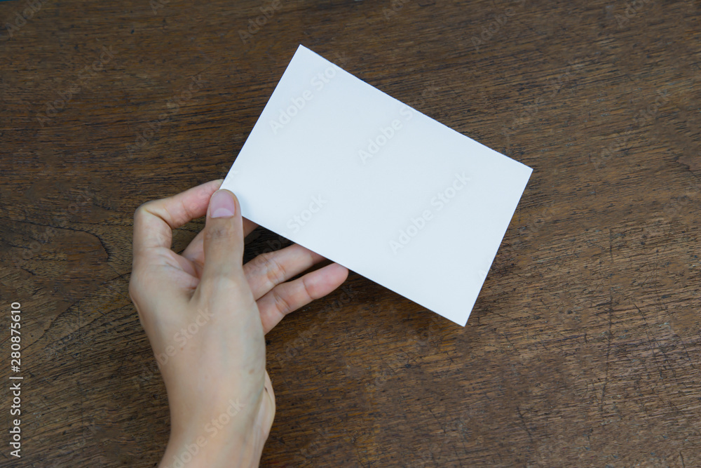 Obraz premium A6 Flyer / Postcard / Invitation Mock-Up - hands holding a blank flyer on a on a wooden table background.