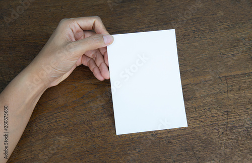 A6 Flyer / Postcard / Invitation Mock-Up - hands holding a blank flyer on a on a wooden table background.