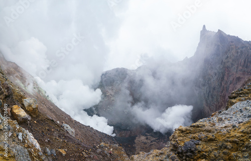 Thick white acrid smoke escapes from the crater of Mutnovsky volcano filled with ashes and stones. Kamchatka, Russia