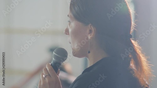 Speaker is giving speech at business event. Adult businesswoman in modern conference hall. Business and entrepreneurship seminar.