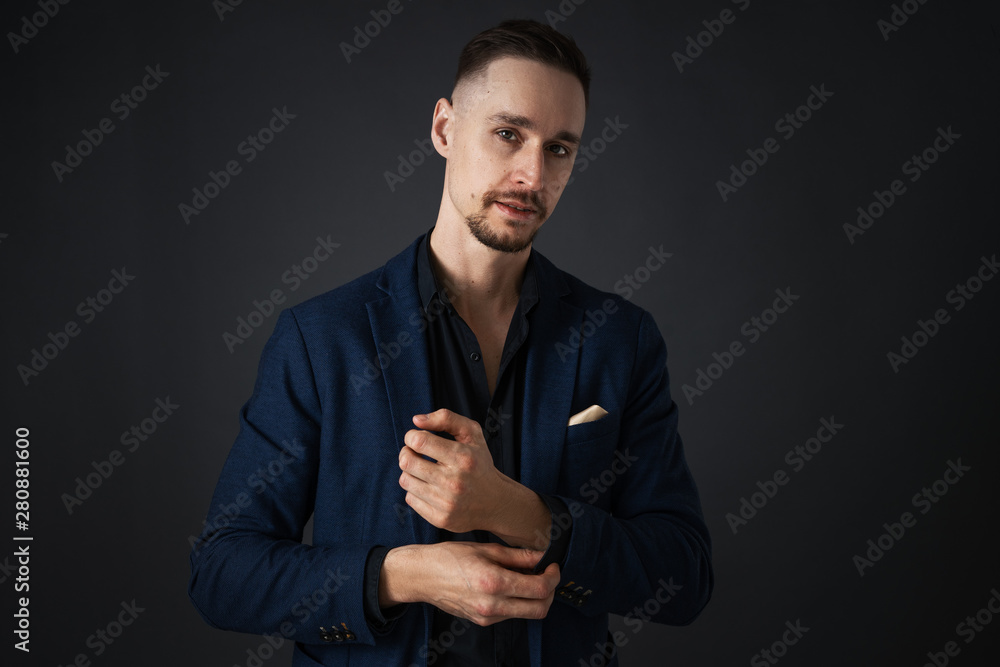 Business negotiations: A young man, a businessman with a bold look, is preparing for negotiations and straightens his jacket. Shows his fists and fighting spirit.