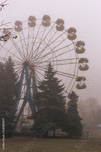 Ferris wheel in an old abandoned park in the autumn in thick fog