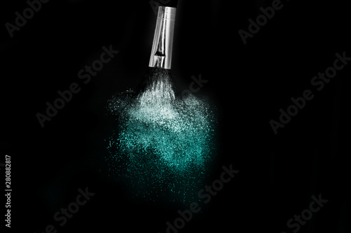 Cosmetic brush with blue cosmetic powder spreading for makeup artist and graphic design in black background
