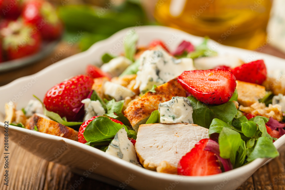 Delicious salad with fried chicken, blue cheese, strawberries and walnuts. Front view.