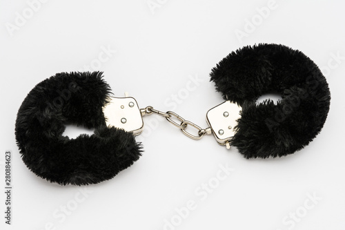 Black furry handcuffs on white background