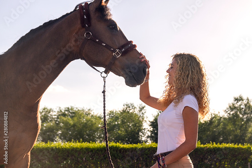 Bild auf Leinwand blonde girl stroking a horse