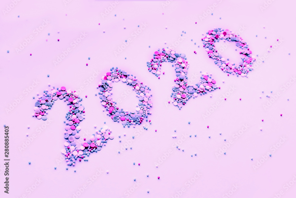 Symbol from numbers 2020 made of colored confetti laying on pink paper background. New year concept. Flat lay composition. Copy space for text or design. Symbol from numbers 2020 made of colored confetti laying on pink paper background. New year concept. Flat lay composition. Copy space for text or design.