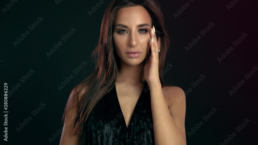 Fashion brunette standing on black wall background in studio Fashion brunette standing on black wall background in studio