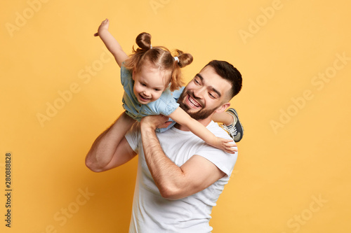 cheerful happy man teaching sweet lovely daughter to fly like a plane. close up photo. isolated yellow background. studio shot, happy moments with best father photo