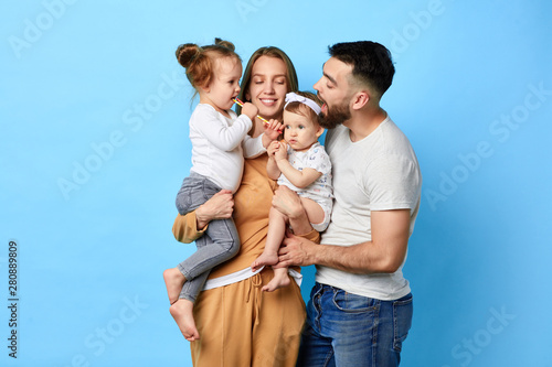 Happy family eating lollipop while standing over blue background. studio shot. close up portrait. happiness, love,strong relationship