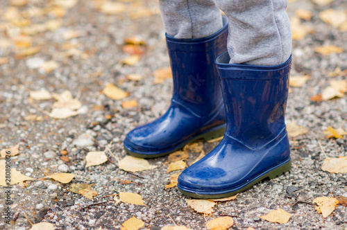 Feet of child in blue rubber boots jumping over a puddle after the rain. Close up of child wellies in autumn weather © matkovci