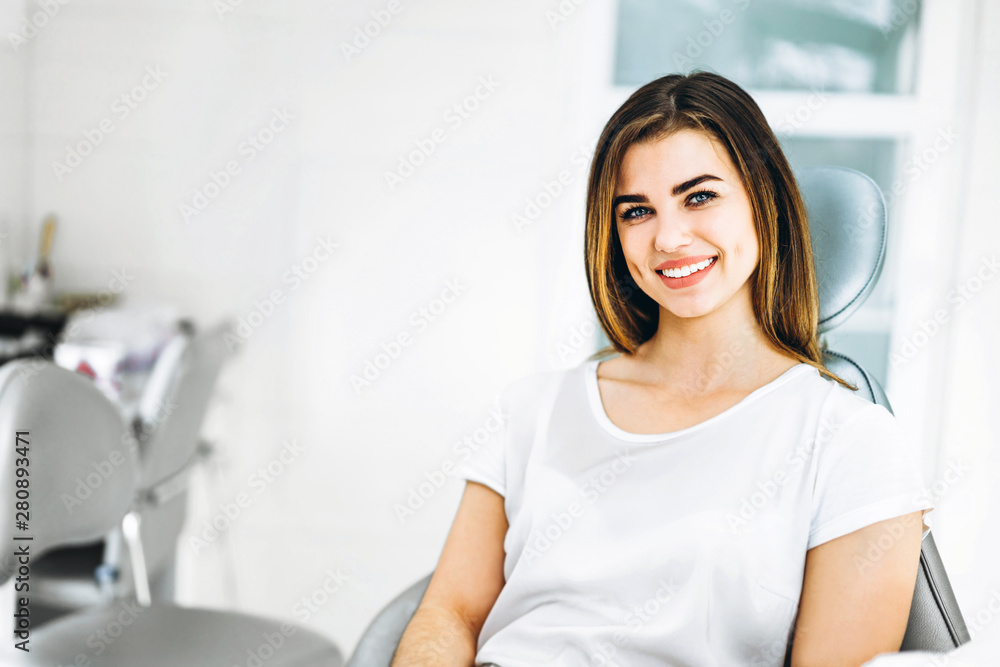 Pretty happy and smiling dental patient sitting in the dental chair at the dental office. Pretty happy and smiling dental patient sitting in the dental chair at the dental office.