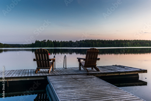 Two wooden chairs at Sunset on a pier on the shores of the calm Saimaa lakein Finland - 3