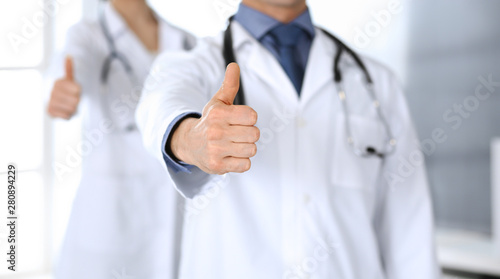 Group of doctors showing thumbs up. Perfect medical service in clinic. Happy future in medicine and healthcare concept