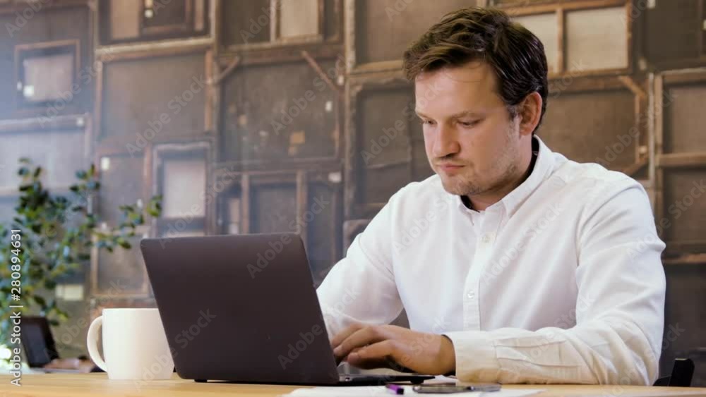 Businessman working on a laptop and talking phone in small business office for startup team. Man upset after unsuccessful negotiations. Looking sad and depressed because of mistakes. Businessman working on a laptop and talking phone in small business office for startup team. Man upset after unsuccessful negotiations. Looking sad and depressed because of mistakes.