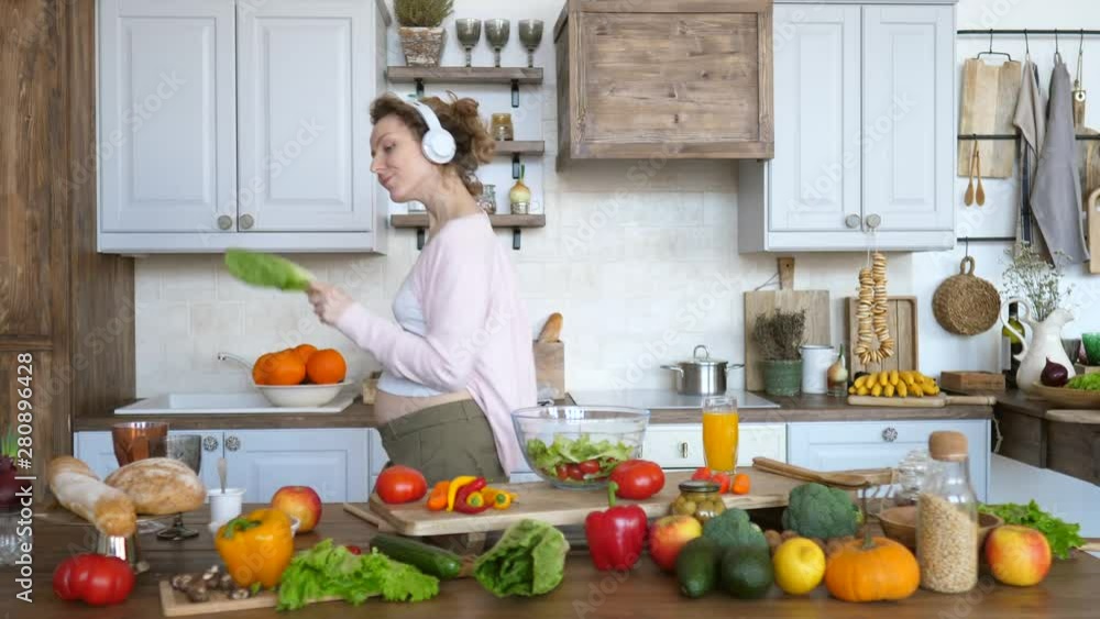 Young Pregnant Woman Dancing In Kitchen While Cooking Healthy Organic Vegan Food. Young Pregnant Woman Dancing In Kitchen While Cooking Healthy Organic Vegan Food.