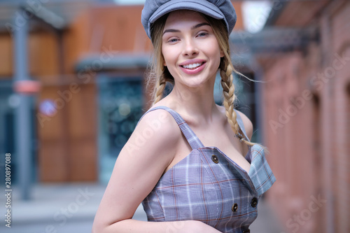 Charming young woman with long blonde hair walks along the street in an old town