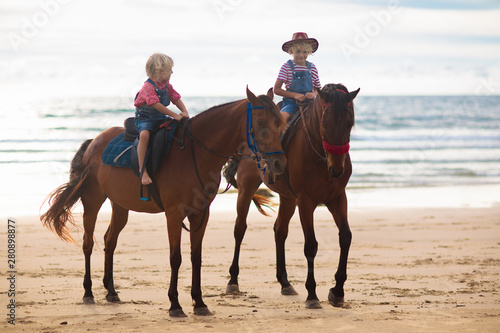 Kids riding horse on beach. Children ride horses. © famveldman