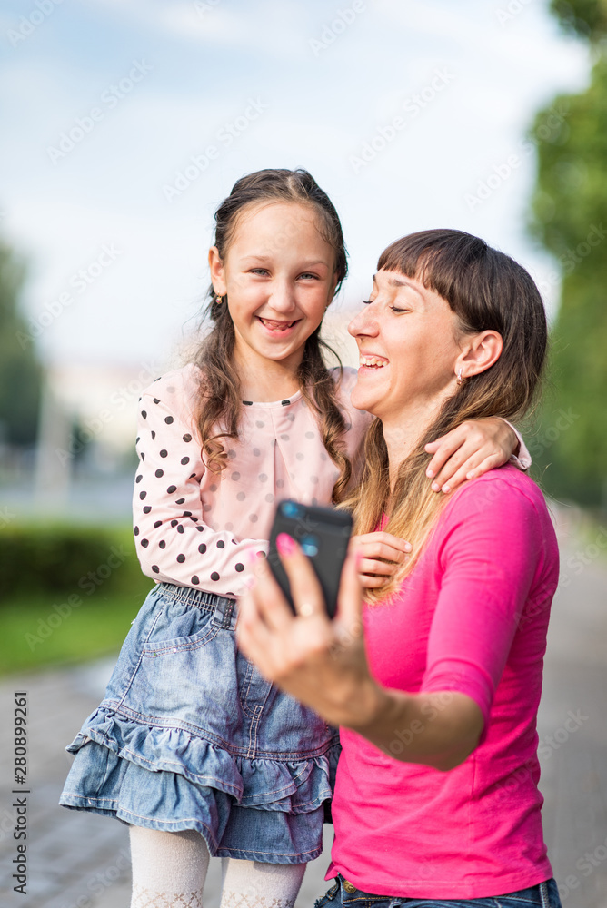 Mom with her little daughter takes a selfie in the park.
