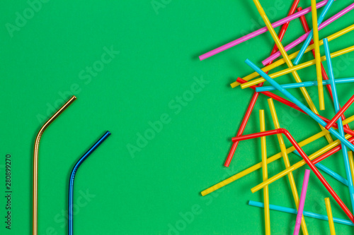 Stainless steel reusable drinking straw with many multicolored plastic straws on light green background © vejaa