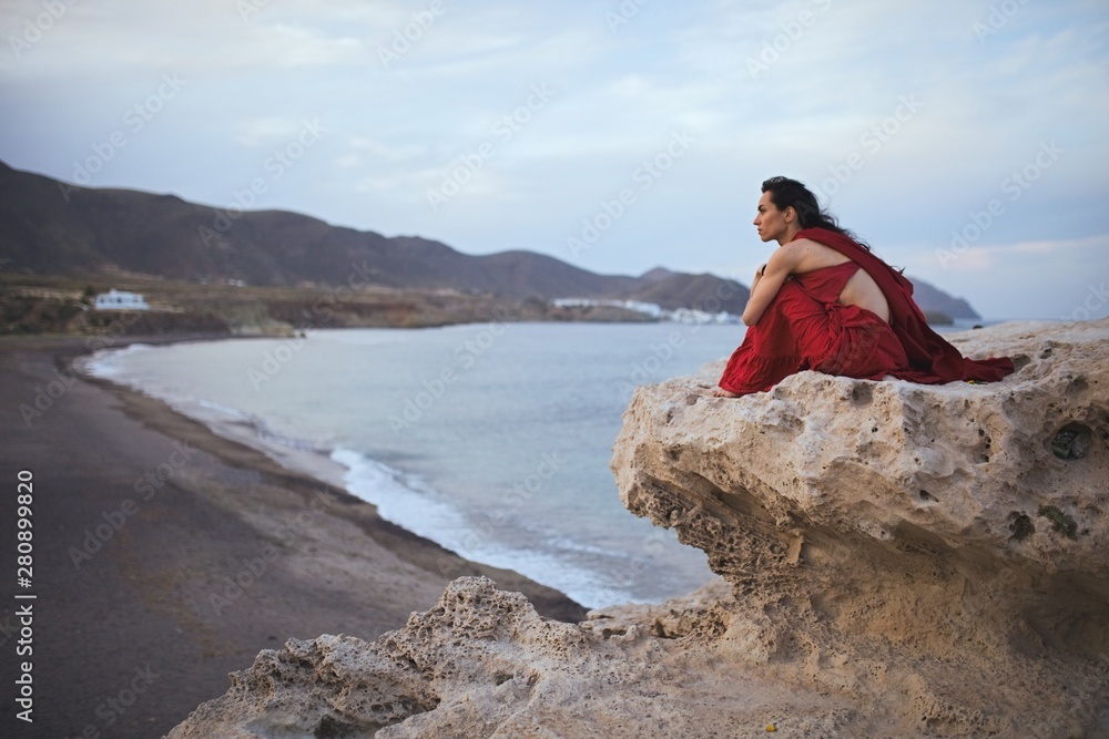 Young brunette woman dancer resting in a rock near the beach