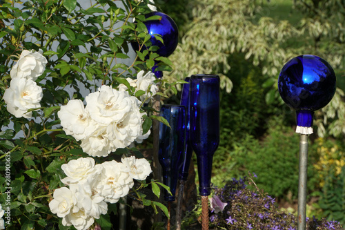 weisse Strauchrose mit blauer Gartendekoration aus Glas photo