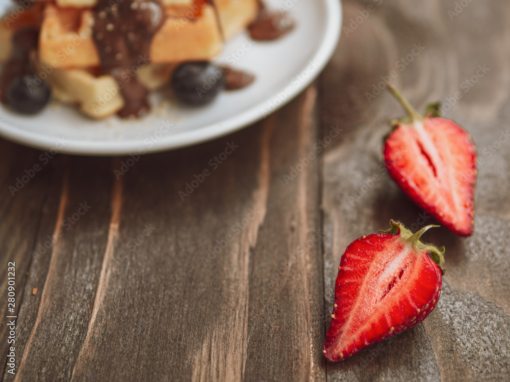 Belgian Waffles with fresh strawberry slices. Closeup on a dark wood