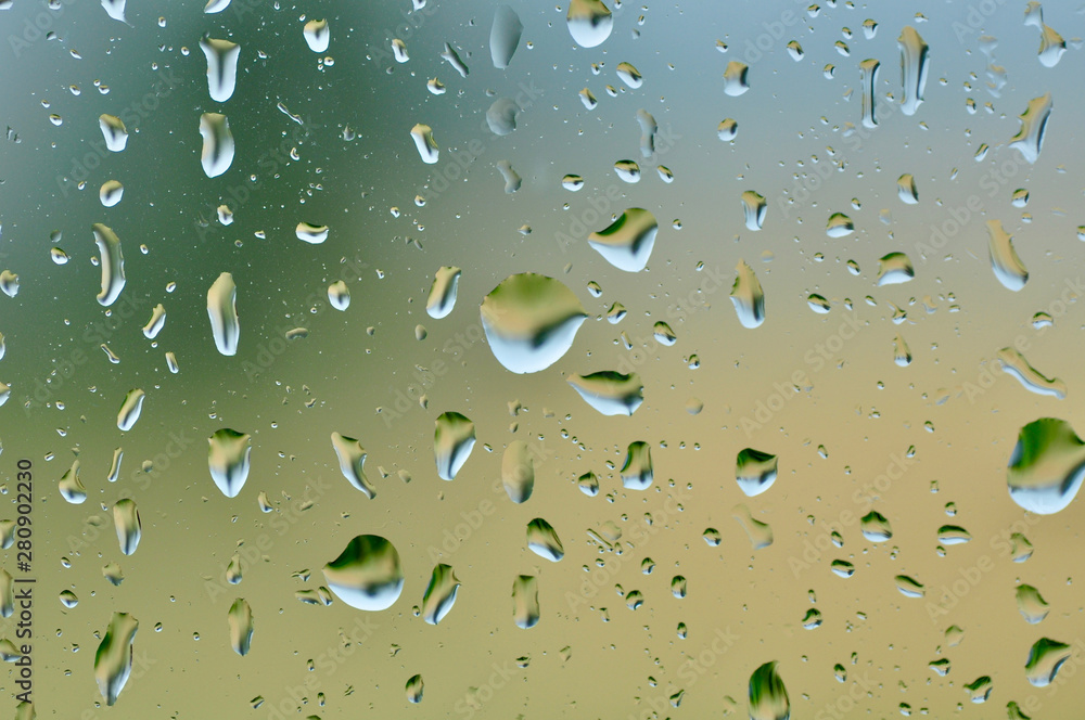 sad day rain drops on glass with yellow green blurred background