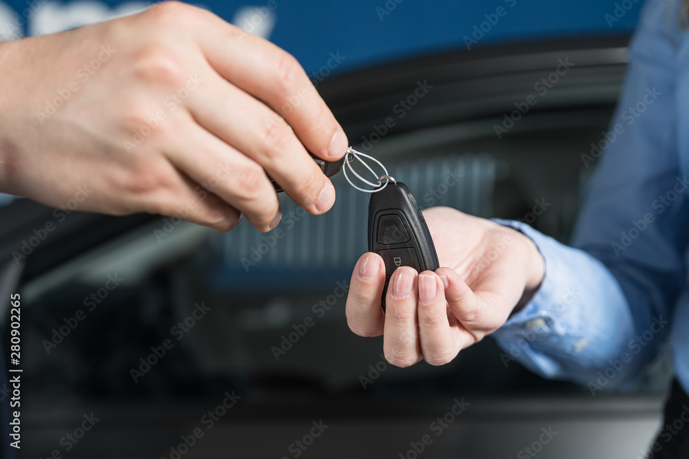 Salesman handing over car keys to new female owner. New or used vehicle buying concept.