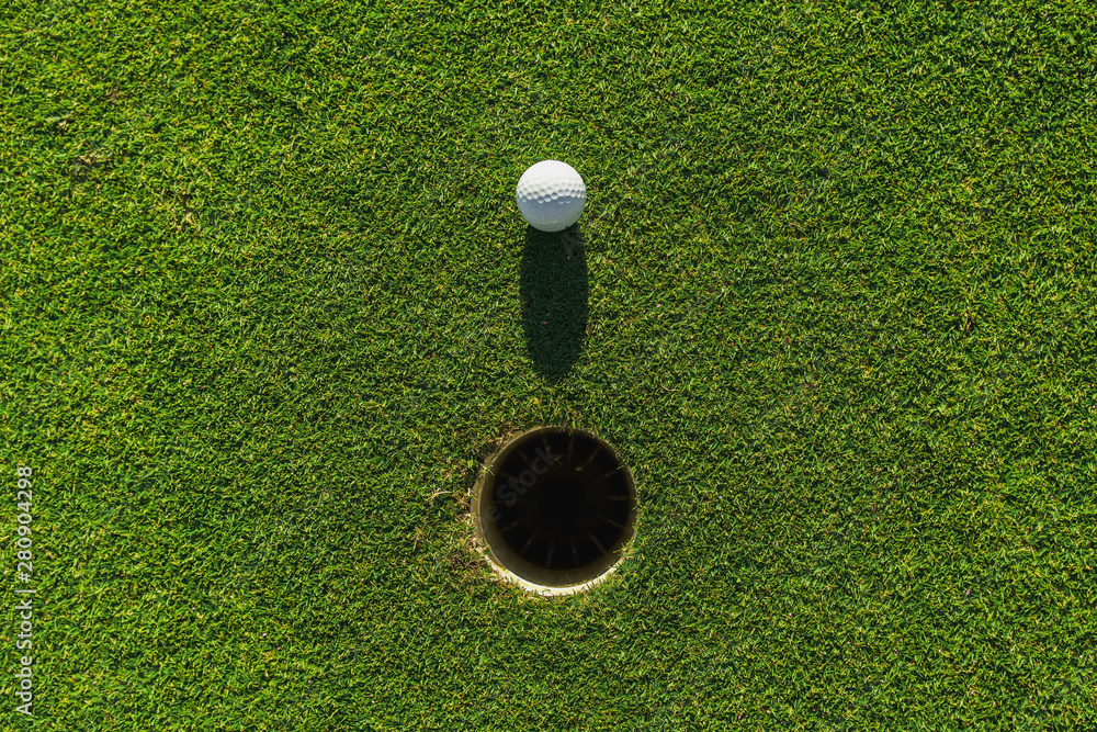 golf ball on green grass with hole and sunlight - obrazy, fototapety, plakaty 