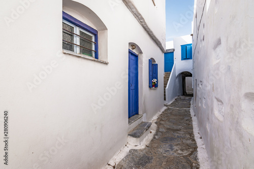 Narrow street between white traditional houses with blue door and window in town centre of Amorgos, Greece. © Nancy Pauwels