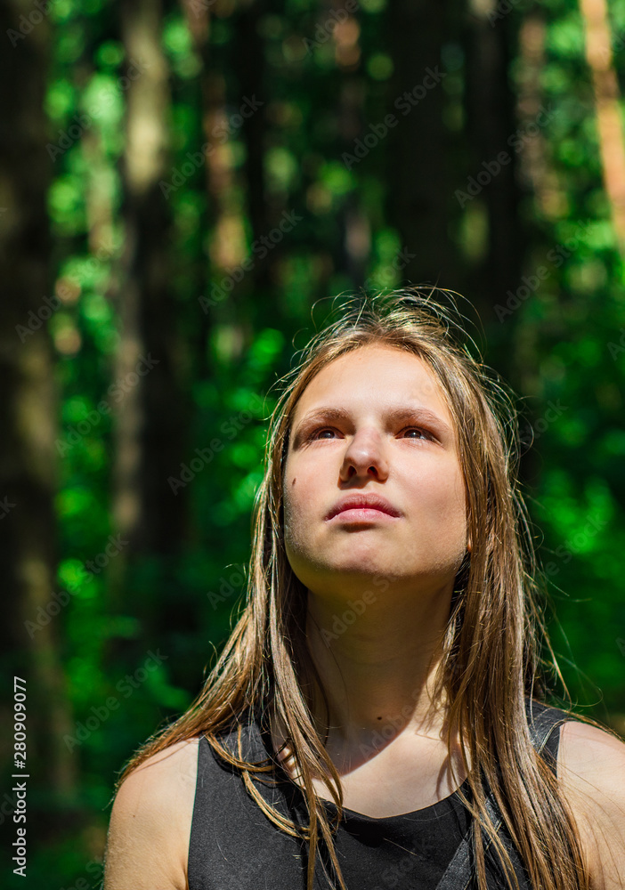 Outdoor portrait of young teenager brunette girl with long hair looking up in forest Outdoor portrait of young teenager brunette girl with long hair looking up in forest