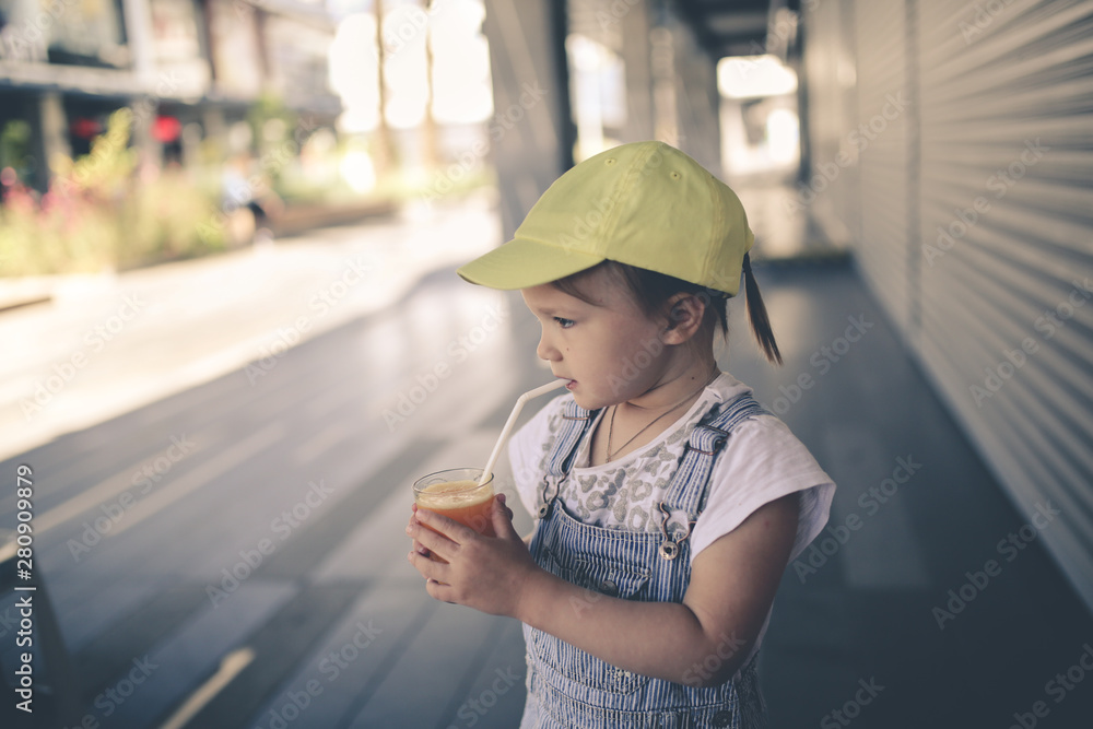 child drinking fresh orange juice through straw