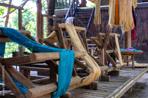 blue and raw silk threads stored on wooden wheels and waiting for fabric production