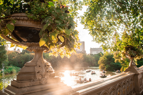 Summer in Central Park New York City seen from historic Bow Bridge with unknown people in row boats in the lake. photo