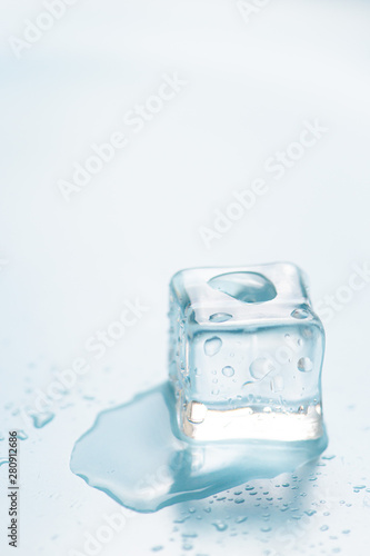 Frozen ice cube on blue background with empty space for text 