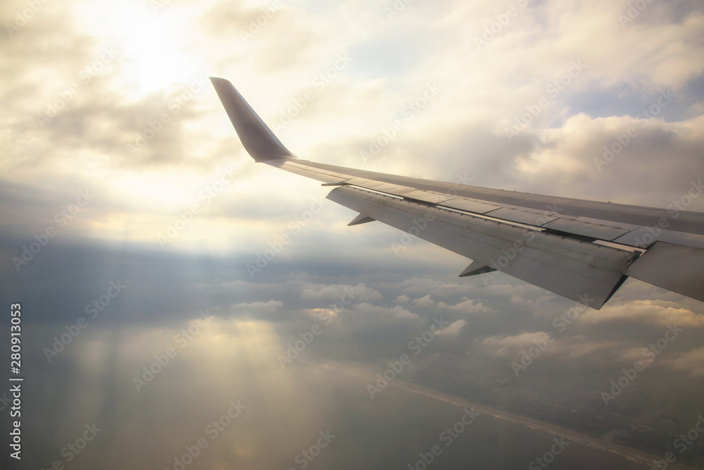 Fototapeta premium Wing of airplane with rays through clouds