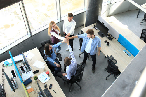 Top view of young modern colleagues in smart casual wear working together while spending time in the office.