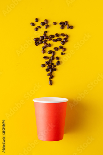 a paper glass for hot drink with coffee beans on color background