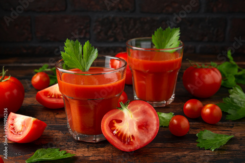 Tomato juice in glass with celery on rustic wooden table