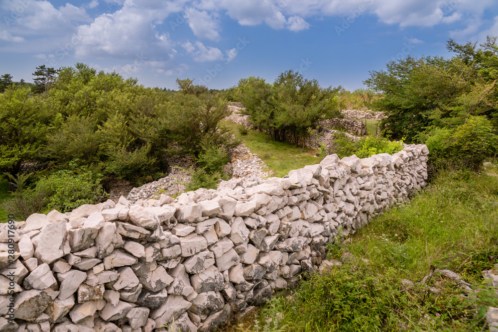 Zaun ausgelegt aus Steinen der Strasse entlang. Kroatien