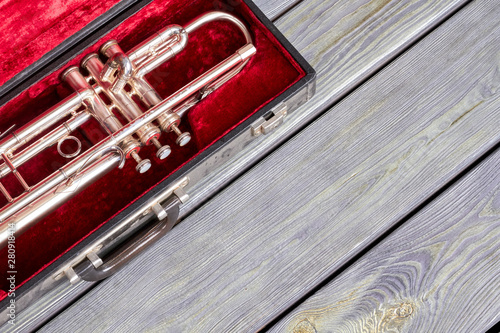 Trumpet in velvet case on wooden background. Professional instrument of symphony music, copy space. Musical instrument of orchestra.