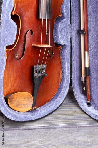 Old violin in case, vertical image. Close up velvet box with viola musical instrument on wooden background.