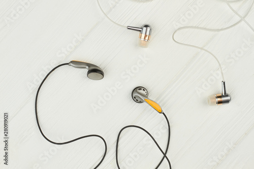 Two pairs of earphones on wooden background. Headphones on light wooden surface. Audio equipment for smartphone.